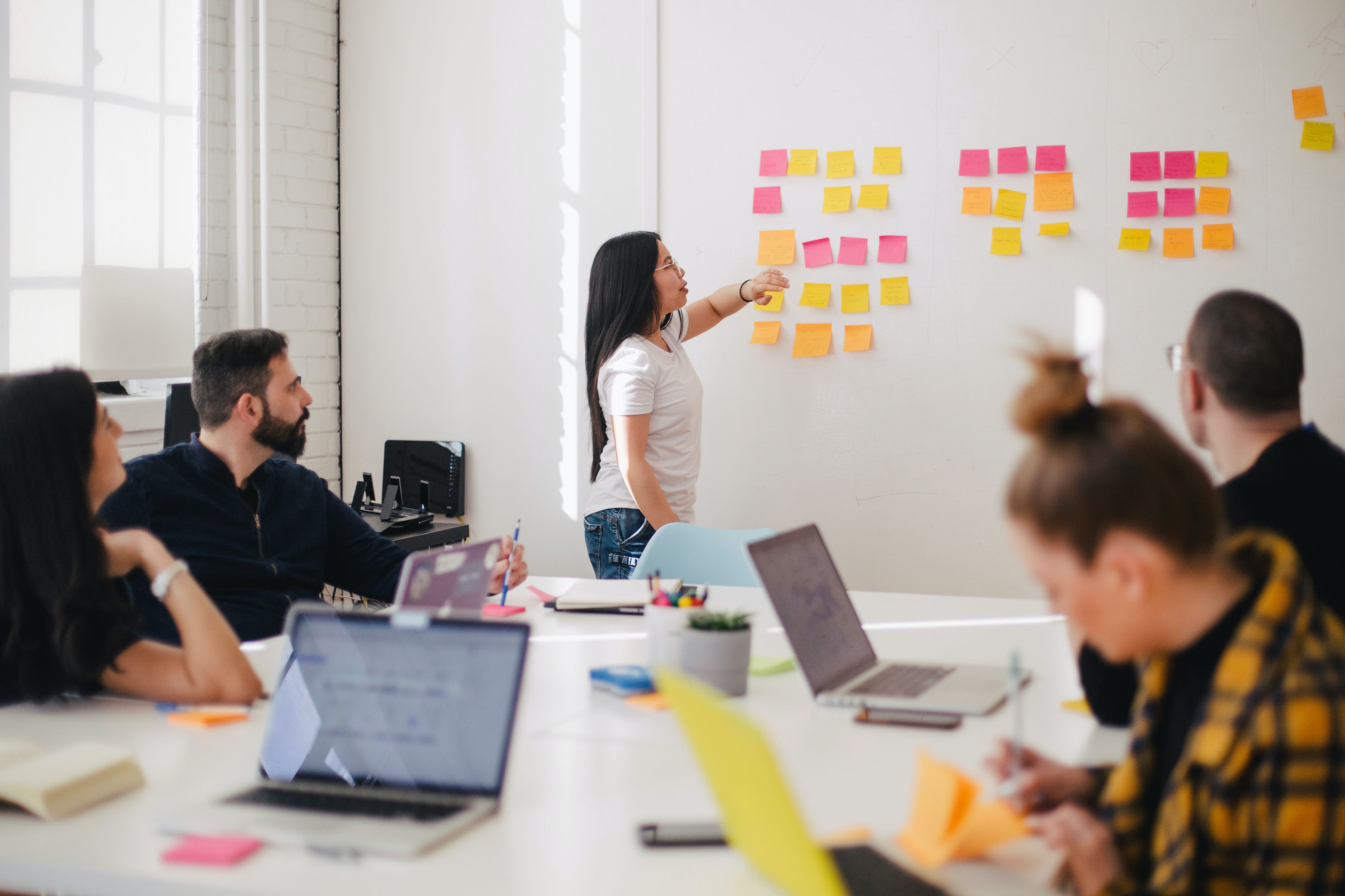 boss placing sticky notes in team business meeting